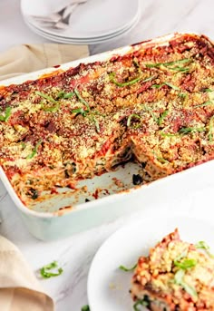 a casserole dish with meat and vegetables in it on a white table next to plates