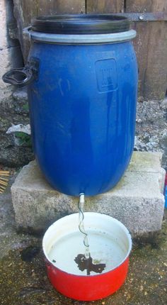 a large blue pot sitting on top of a cement block next to a red and white bowl