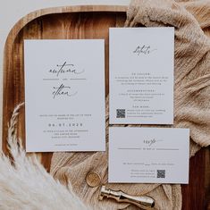 the wedding stationery is laid out on a wooden tray