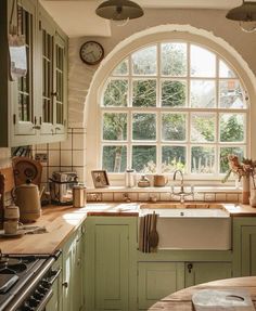 a kitchen with an arched window, sink and stove top oven in front of it