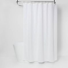 a white shower curtain hanging on a metal rod next to a toilet and bathtub