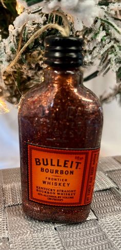 a bottle of bourbon sits on a table next to some branches and lights in the background