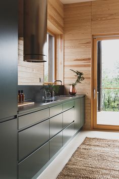 a modern kitchen with stainless steel appliances and wood paneling on the walls, along with an area rug