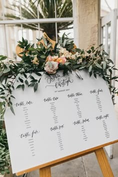 a seating sign with greenery and flowers on it