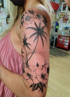 a woman's arm with flowers and palm trees on it