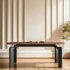 a wooden table sitting on top of a hard wood floor next to a potted plant