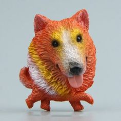 an orange and white dog figurine with its tongue out on a gray surface