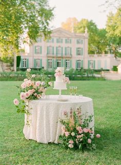 a wedding cake sitting on top of a table in front of a large white house