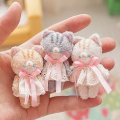 three small stuffed animals are in the palm of someone's hand with pink bows