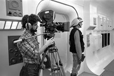 black and white photograph of two men with headphones on in front of a camera