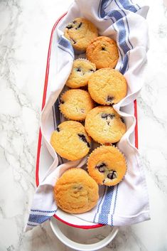 blueberry muffins in a red and white dish on a marble countertop