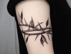 a black and white photo of a branch with leaves on it's arm that is wrapped in barbed wire