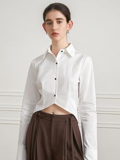 Soft and structured, this slim fitting shirt has sharp collars and tucked detail at waist. It has unique, asymmetrically cut hem design.  - Cotton and nylon blend fabric- Open collars and button fastenings through front- Long sleeves with layered cuffs- Cut out, flare style hem design- Trendy cropped length Fitted Asymmetrical Office Blouse, Fitted Asymmetrical Office Top, Asymmetrical Fitted Blouse For Work, Fitted Asymmetrical Blouse For Workwear, Modern Fitted Asymmetrical Blouse, Chic Fitted Shirt With Asymmetrical Hem, White Workwear Shirt With Asymmetrical Hem, White Shirt With Asymmetrical Hem For Work, Spring Fitted Shirt With Asymmetrical Hem