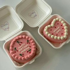 three pink birthday cakes in plastic containers with writing on them