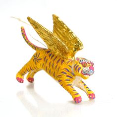 a yellow tiger figurine with wings on it's head and tail, against a white background