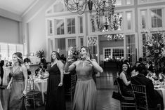 a group of women standing next to each other in front of a chandelier