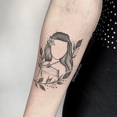 a woman's arm with a black and white portrait tattoo on the left forearm