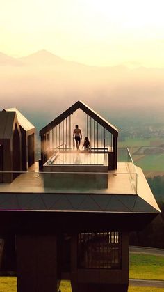 two people standing on the roof of a building with mountains in the backgroud