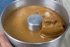 a hand holding a metal bowl filled with liquid