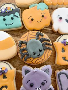 halloween decorated cookies are arranged on a wooden table with ghost, cat and spider decorations