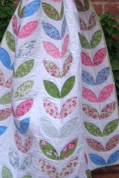 a white quilt with pink, blue and green leaves on it