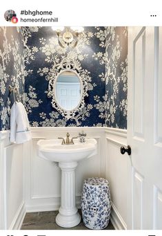 a white pedestal sink sitting under a mirror in a bathroom next to a blue and white wall