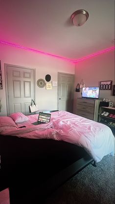 a bed with pink sheets and pillows in a room that has lights on the ceiling