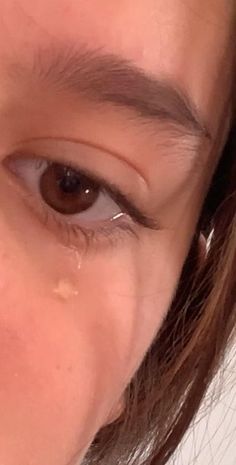 a close up of a woman's eye with tears on her eyes and eyebrows