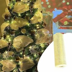 a christmas tree decorated with gold ribbon and ornaments next to an open spiral bound book