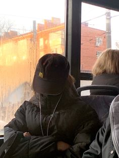 two people sitting on a bus with their backs to each other, looking out the window