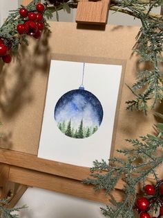 an ornament hanging from a christmas tree with red berries and greenery around it