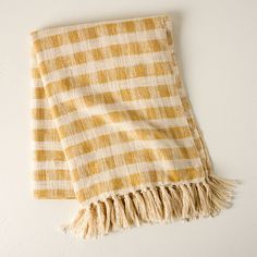 a yellow and white checkered towel hanging on the wall with fringes around it