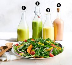 a salad with dressing ingredients on the side and in bottles next to it for dressing