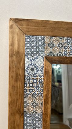 a wooden frame with a blue and white tile design on the front, along with a mirror