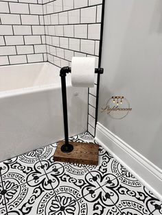 a bathroom with black and white tiles on the floor, toilet paper roll holder next to it