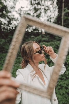 a woman is looking into a mirror with her sunglasses on