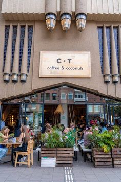 people sitting at tables in front of a coffee and coconut shop