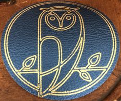 an owl emblem is on the back of a wooden chair with blue leather upholstered