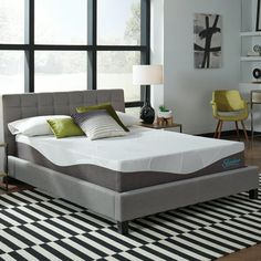 an image of a bed that is in the middle of a room with black and white rugs