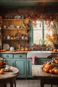 Welcome to this enchanted autumn-inspired rustic kitchen, where the magic of fall pervades the air. A stunning garland of autumn leaves and bountiful harvest decorates the weathered wooden shelves and cabinetry. The farmhouse-style sink and turquoise cabinets evoke a vintage charm. Hearty pumpkins, squash, and foliage are artfully strewn across the countertops and a round wooden table. Elegant china is displayed alongside rustic earthenware, embodying the warmth of home. Autumnal House, Decorate Thanksgiving, Pearl Kitchen, Rustic Home Decor Kitchen, Turquoise Cabinets, Pumpkin Kitchen, Autumn Kitchen