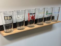 a row of beer glasses sitting on top of a wooden shelf