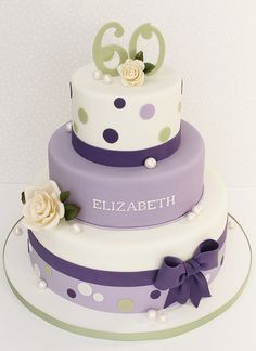 a three tiered cake with polka dots and flowers on the top is decorated in purple, white and green