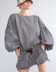 Geneva gingham cotton ballon sleeve blouse.    - drop shoulder with sheering  - balloon sleeve with elastic cuffs  - bateau neckline  - loose flowy fit  - gingham print  - breathable polished cotton  - fabric content: 100% cotton voile  - care instructions: machine wash cold and hang dry    fit: model is 5'9" and wears a size s.    size s measurements:    - length: 24.5"    complete the look: gingham cargo shorts Chic Cotton Puff Sleeve Top With Elastic Sleeves, Chic Smock Blouse With Balloon Sleeves, Chic Smocked Blouse With Balloon Sleeves, Chic Spring Tops With Elastic Cuffs, Chic Gingham Long Sleeve Blouse, Summer Blouson Puff Sleeve Top, Chic Long Sleeve Gingham Blouse, Summer Long Sleeve Puff Sleeve Top With Smocked Cuffs, Summer Tops With Smocked Cuffs And Lantern Sleeves