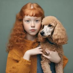 a girl with red hair holding a poodle in her arms and looking at the camera