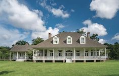 a large white house sitting in the middle of a lush green field on a sunny day