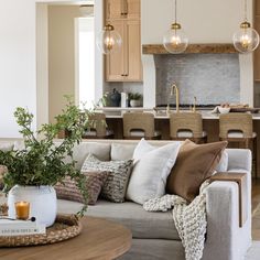 a living room filled with furniture next to a kitchen and dining room table in front of an open floor plan