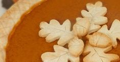 there is a pie with leaves on it and some cookies in the shape of snowflakes