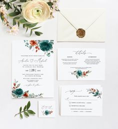 the wedding stationery is laid out with flowers and greenery