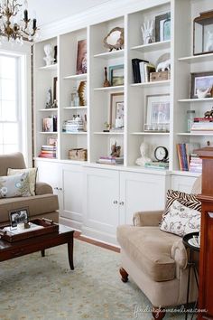 a living room filled with lots of white bookshelves