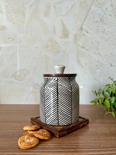 a black and white vase sitting on top of a wooden table next to crackers